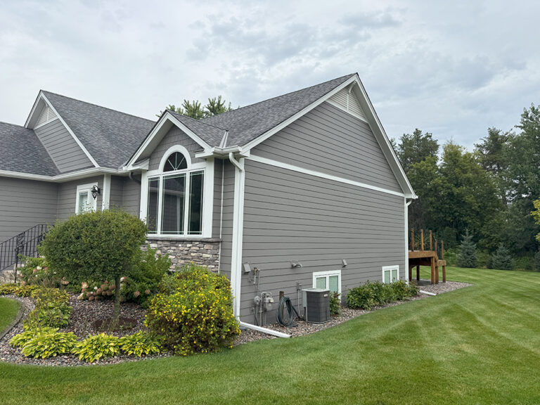 Side view of Lino Lakes home with James Hardie Aged Pewter siding, Arctic White trim, and cultured stone accents.